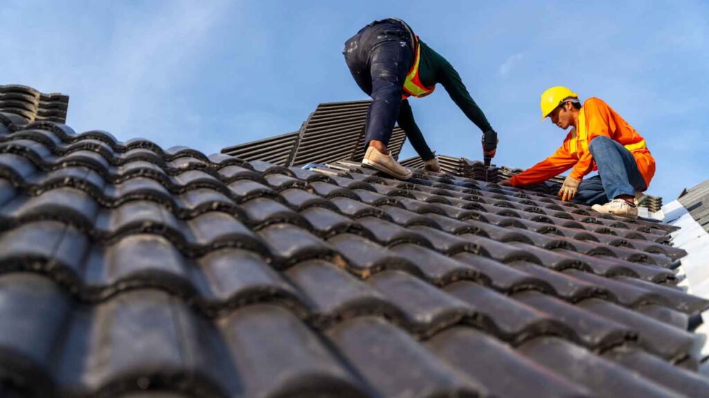 Roofing contractors installing durable tile shingles on a home