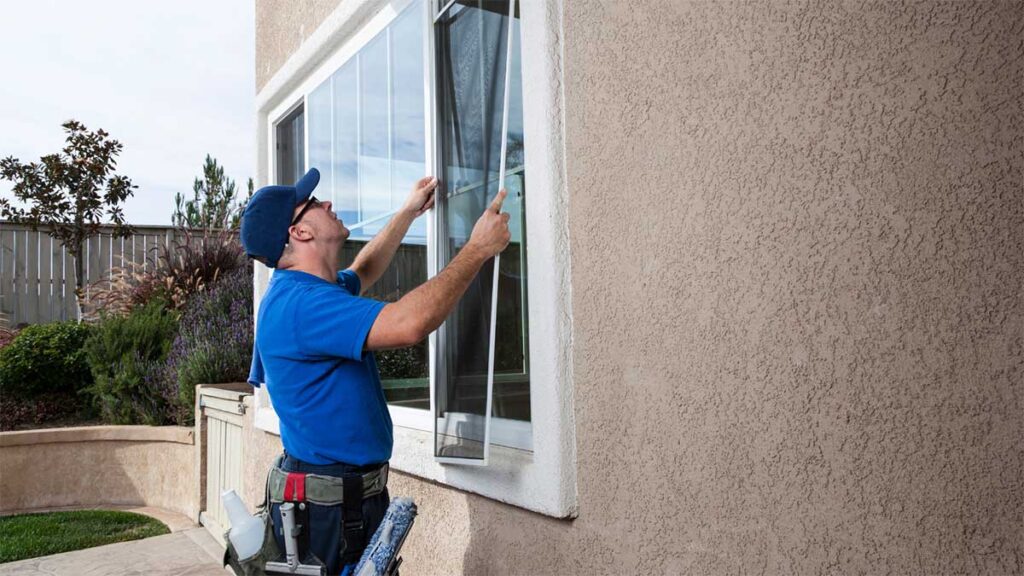 Technician installing a window screen on a residential home