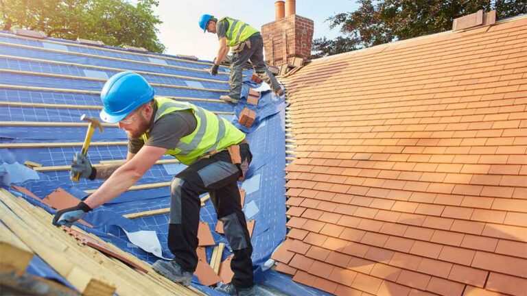 Roofers installing new shingles on a house roof.