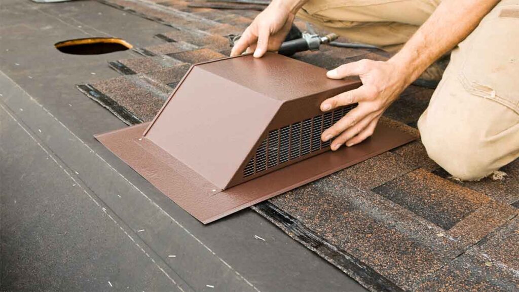 Worker installing a roof vent on asphalt shingles