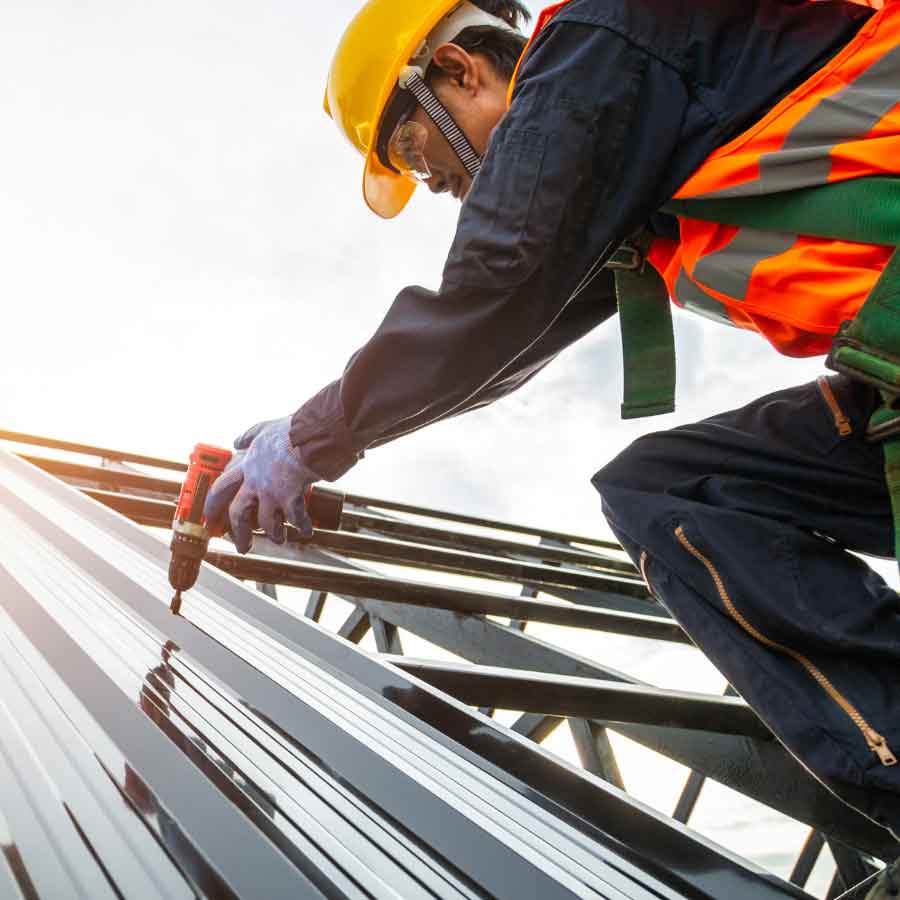 Construction workers installing a metal roof with power tools