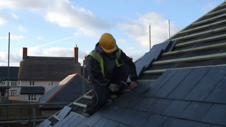 Roofer installing slate tiles on a pitched roof
