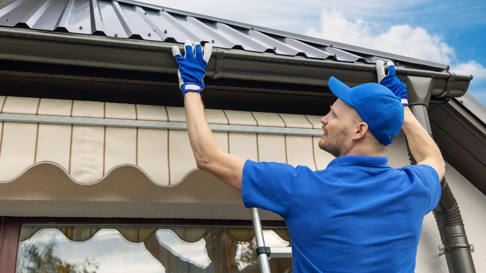 Roofing contractor inspecting and adjusting a metal gutter