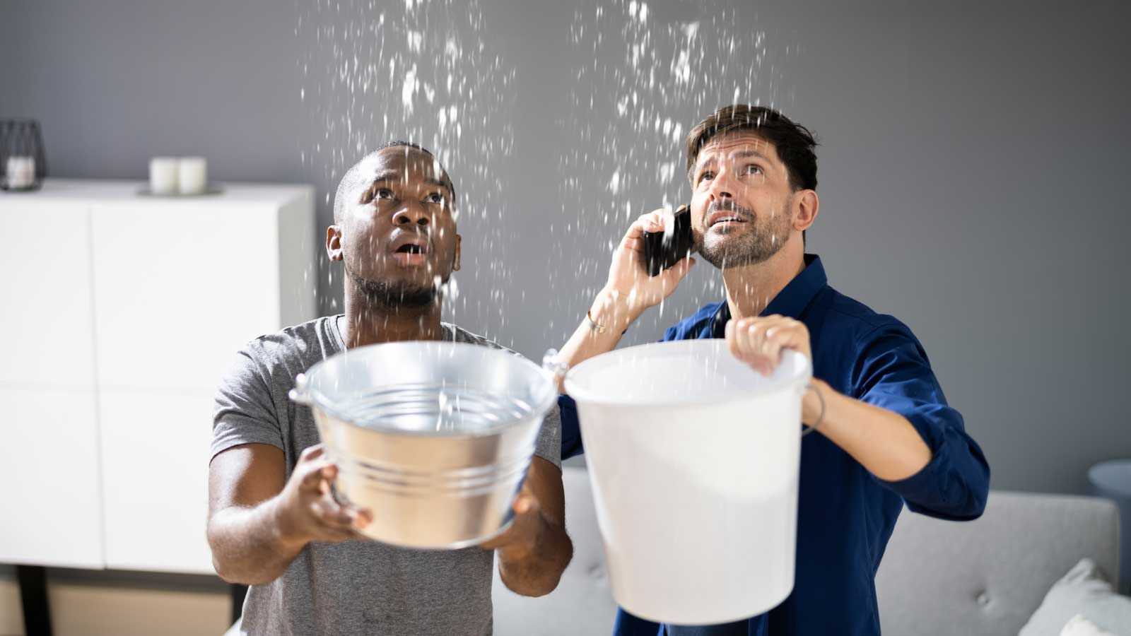 Men catch water from a leaking roof with buckets.