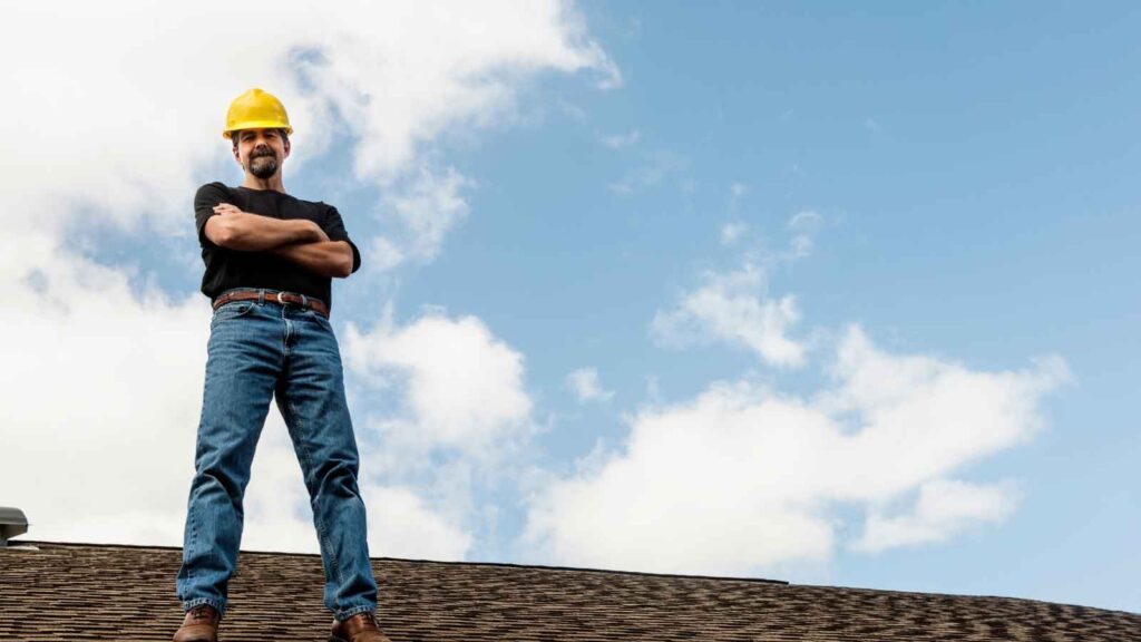 Roofing contractor in a yellow hard hat standing on a rooftop