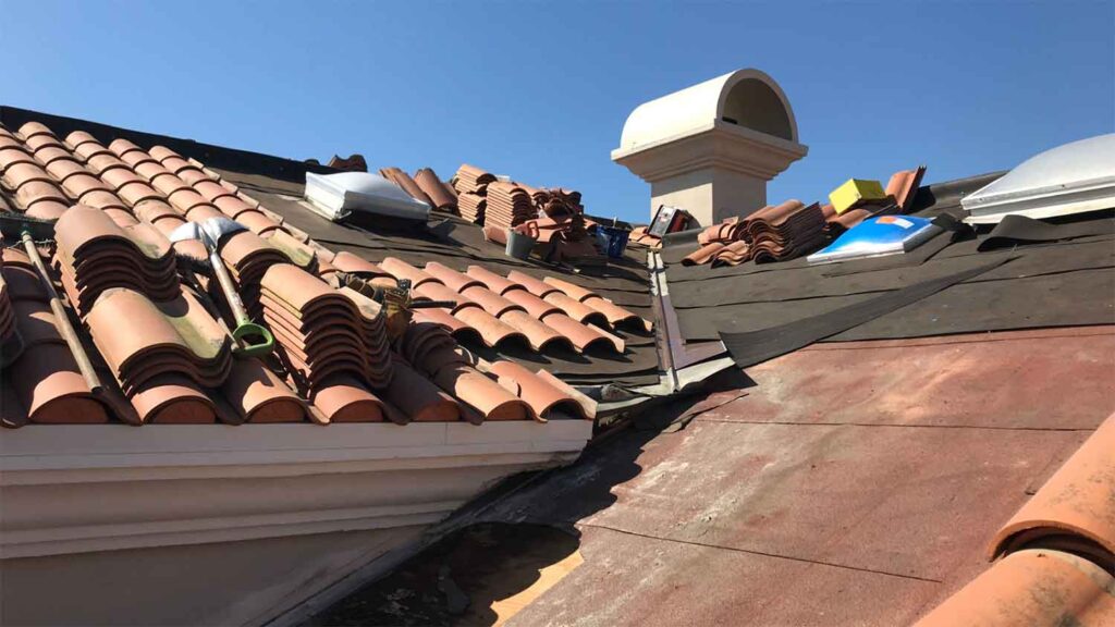 Clay tile roof under repair with stacks of tiles and tools
