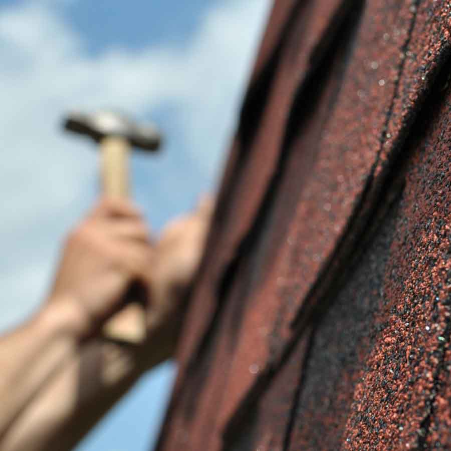 Close-up of asphalt shingles being nailed during roof repair.