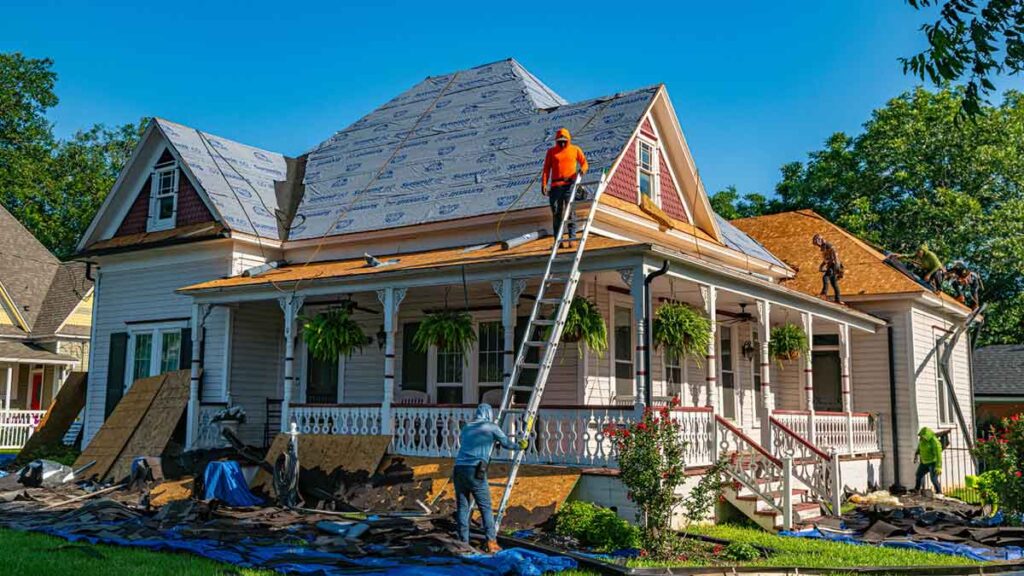 Roofers working on a house, installing new roofing materials.