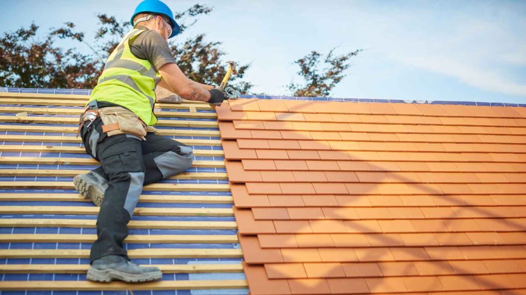 A worker installing clay tiles on a roof.