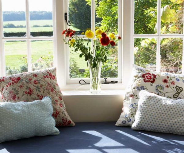 Cozy window seat with cushions overlooking a sunny garden.