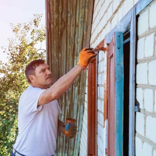 Experiencedexteriorpaintercarefullypaintingawindowfram Experiencedexteriorpaintercarefullypaintingawindowfram