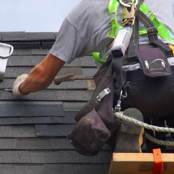 Roofersecuringshingleswhilewearingsafetygearonasteeproo