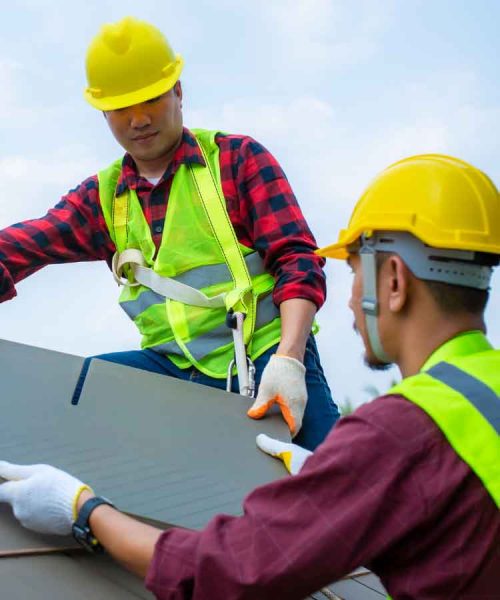 Two workers installing roof tiles