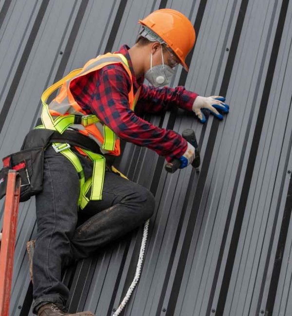 Worker installing and securing a metal roofing panel safely